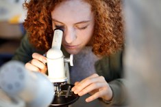 Studente Bio-ingenieurswetenschappen met oude microscoop